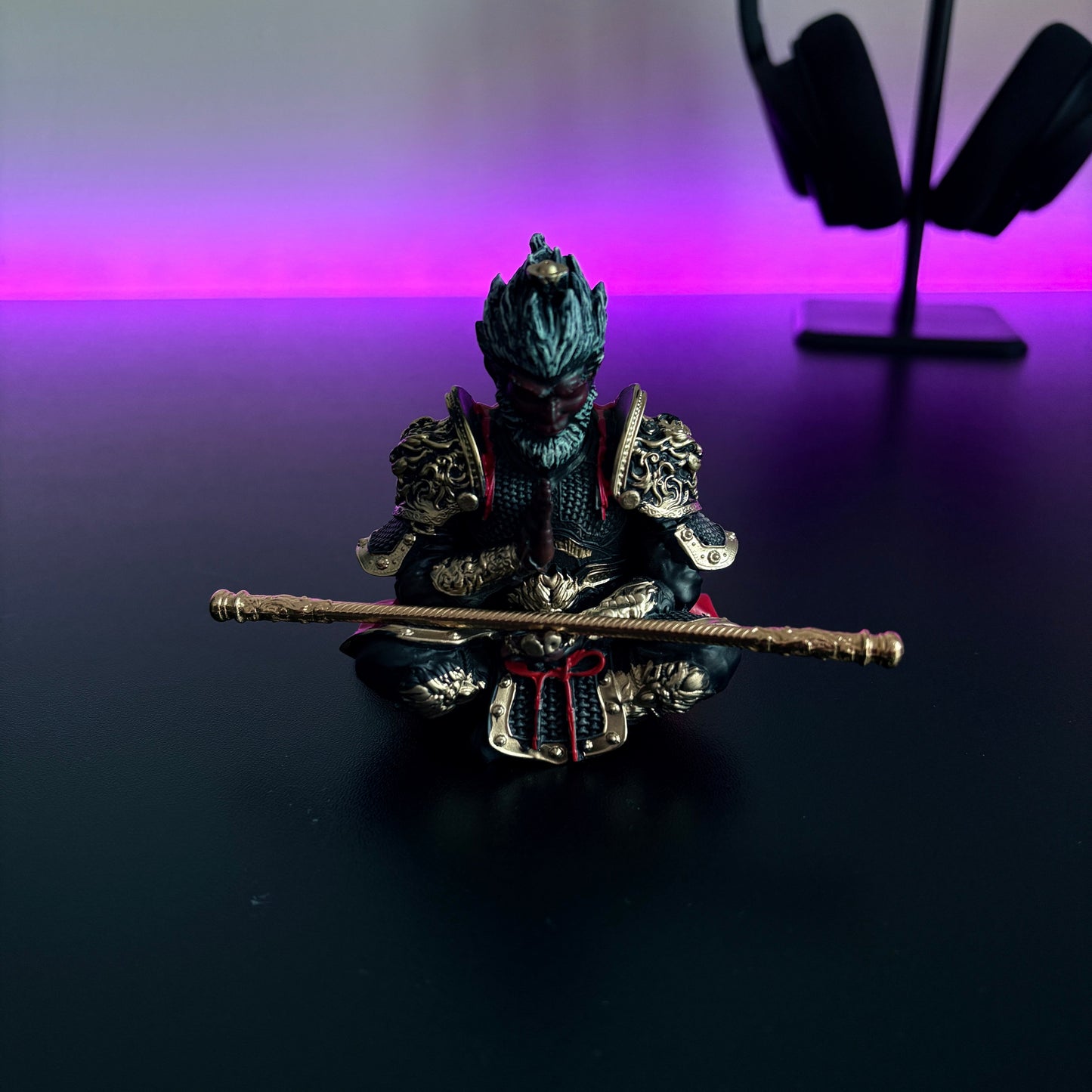 Decorative figurine of a warrior with a staff on a reflective surface, with a blurred background.